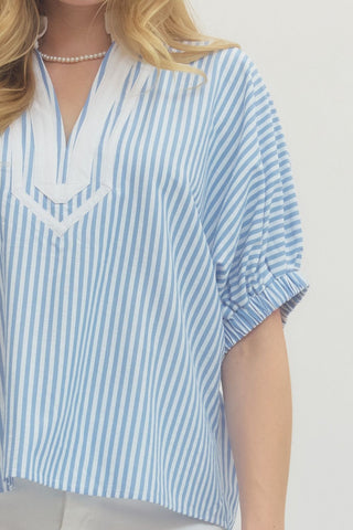 Woman wearing a blue and white striped shirt with a plain background