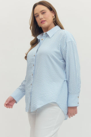 Woman wearing a light blue striped shirt against a white background