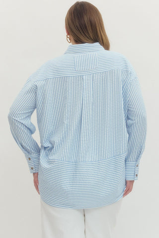 Woman wearing a light blue striped shirt against a white background