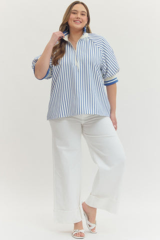 Woman wearing a blue and white striped shirt and white pants on a white background