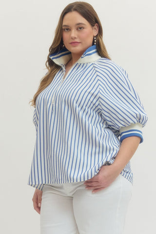 Woman wearing a blue and white striped shirt with rolled-up sleeves against a plain background