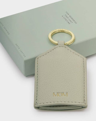 Gray leather keychain with 'MOM' engraving on a light green box background