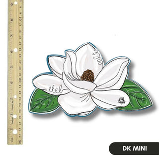 White flower decal with green leaves next to a ruler on a white background