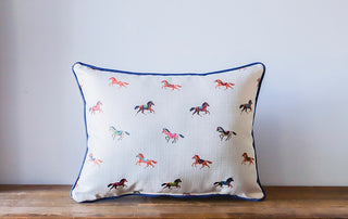 Decorative pillow with horse patterns on a wooden surface and light gray background