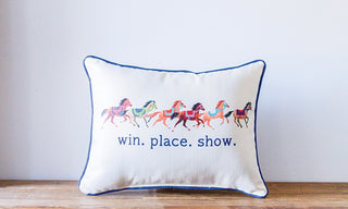 Decorative pillow with horse illustrations and text 'win. place. show.' on a plain background