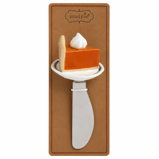 A novelty cake slice prop with a white frosting swirl on a slice of orange pumpkin pie, mounted on a brown cardboard backing that reads 'mudpie'.