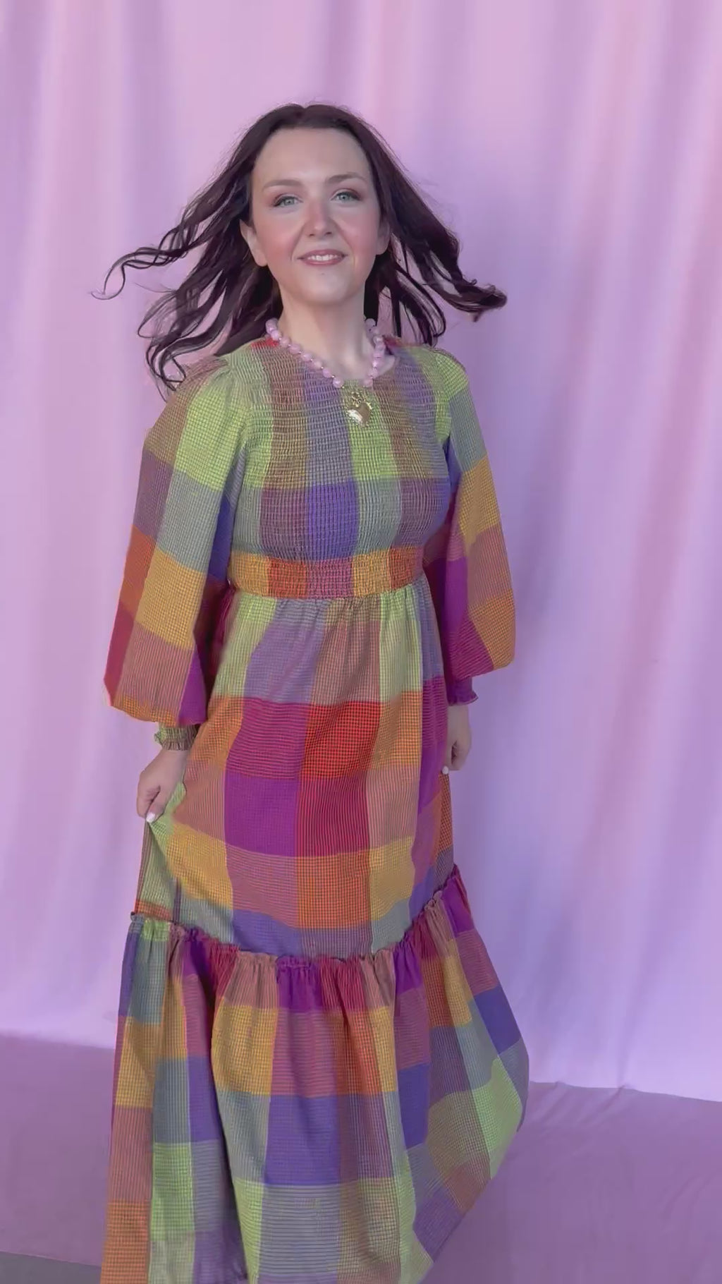 girl wearing plaid dress on a pink background