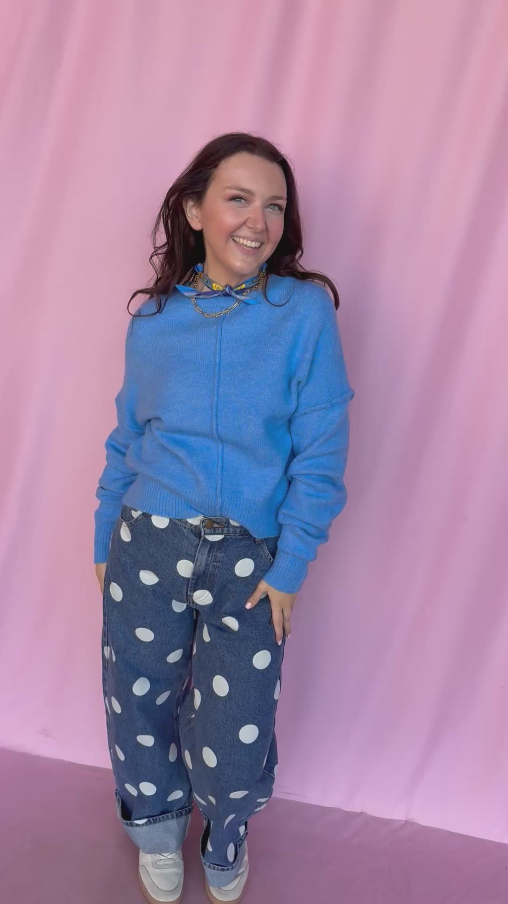 girl wearing blue sweater on a pink background