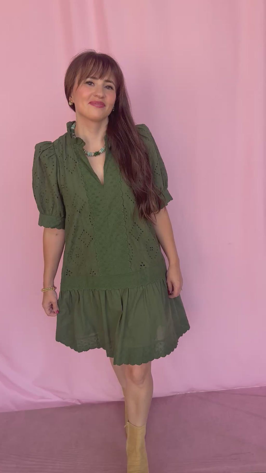 woman wearing a green dress on a pink background